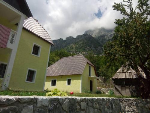 瓦勒博内Bujtina Ahmetaj的黄色的房子和山地建筑的背景