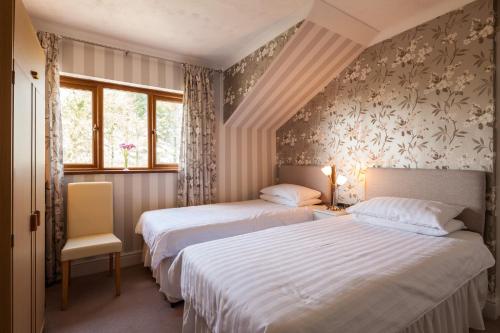 桑德斯富特Langdon Farm Guest House的带2扇窗户的客房内的2张床