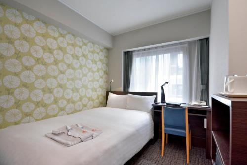 东京新宿普樂美雅凱賓酒店的配有一张床和一张书桌的酒店客房