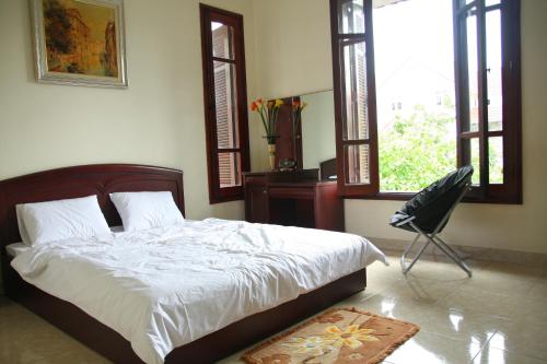 下龙湾Hạ Long Lily Homestay的一间卧室配有一张床、一把椅子和窗户。