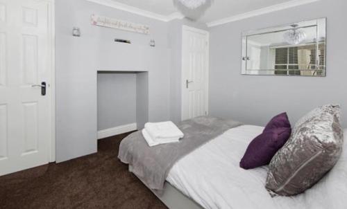 荷尼湾Imperial House Holiday Let的一间卧室配有一张带紫色枕头和镜子的床