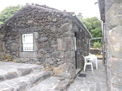 普赖尼亚德拜舒Casas de Campo HousesInPico的石头建筑,配有桌子和白色椅子