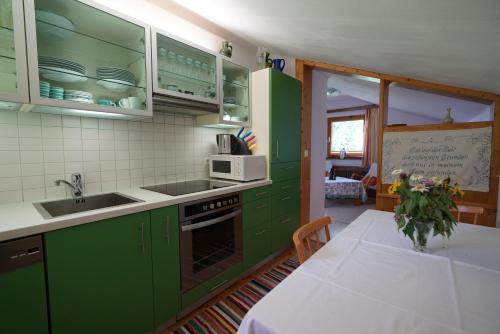 拉姆绍达赫斯坦豪斯瓦尔特劳特公寓的厨房配有绿色橱柜和一张带白色桌布的桌子