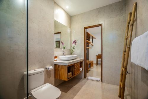 乌布柚木小屋旅馆的一间带卫生间、水槽和镜子的浴室