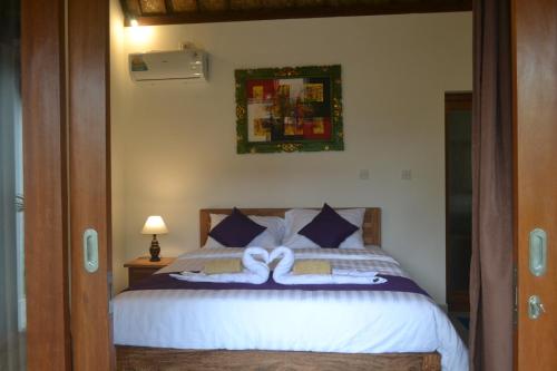 乌布Buda Cottage Ubud的一间卧室配有带白色床单和蓝色枕头的床。