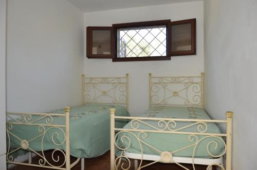 圣卡特琳娜迪纳德Portoselvaggio Villa Martina的带窗户的客房内的两张床