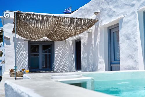 KardhianíLiving Theros Luxury Suites的一座带游泳池和草伞的白色房子