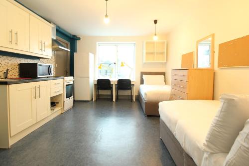 都柏林Tom Dick and Harriet's Accommodation的一间设有两张床的小房间和一间厨房,一间设有床铺的房间
