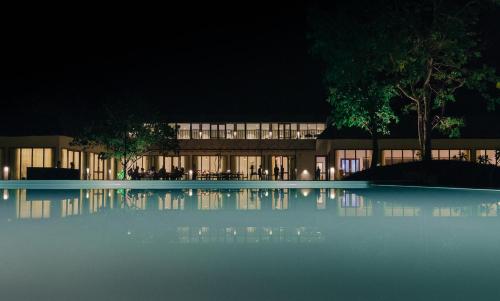 加尔加Saraca Resort & Spa Corbett的一座晚上设有游泳池的建筑