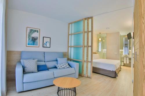 洛斯阿尔卡萨雷斯Apartamentos 525的一间带蓝色沙发的客厅和一间卧室