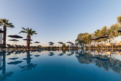 帕拉利亚卡泰里尼斯Mythic Summer Hotel的一个带遮阳伞和桌椅的游泳池