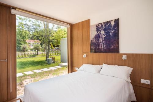 圣克鲁斯德奥莱罗斯Bungalow Camping Los Manzanos的卧室设有白色的床和大窗户
