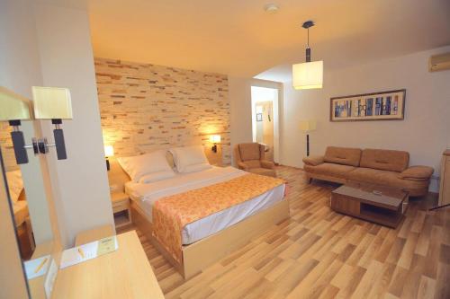 普里什蒂纳比诺丘酒店的一间卧室配有一张床、一把椅子和一张沙发