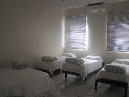 伊瓜苏普萨达跨提宾馆的配有白色墙壁和窗户的客房内的三张床