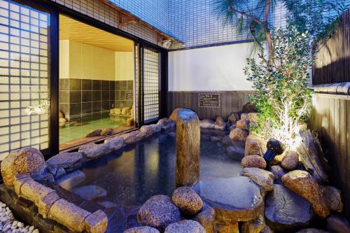 仓敷Dormy Inn Kurashiki Natural Hot Spring的一座建筑前的岩石水池