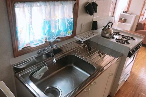北谷町Mini Chula Inn的厨房配有不锈钢水槽和炉灶。