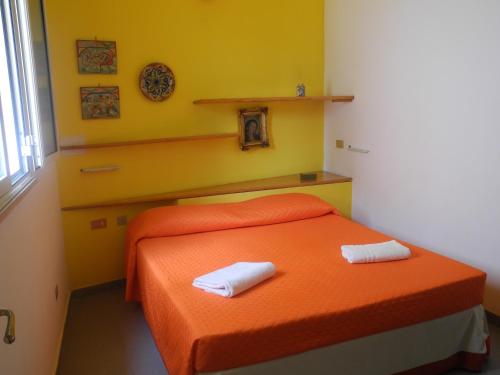 兰佩杜萨Cala Maluk的一间卧室配有橙色床和2条毛巾