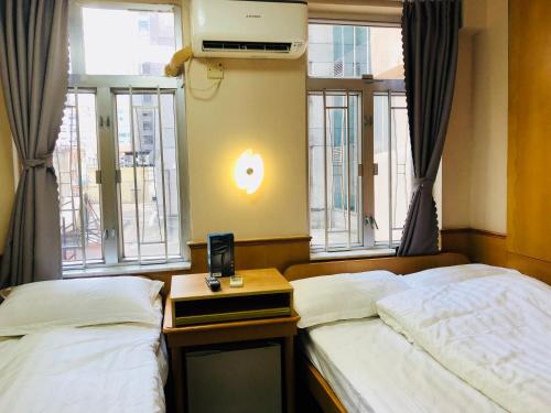 香港祥泰旅馆的带窗户和床头柜的客房内的两张床