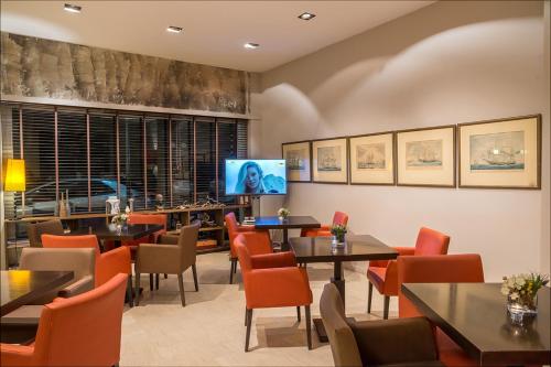 伊泰阿加里尼酒店的餐厅设有桌椅和平面电视。