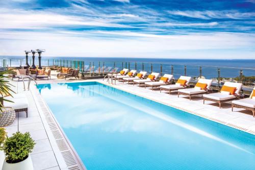 多伦多多伦多X睿智集酒店的一个带椅子的游泳池,背景是大海