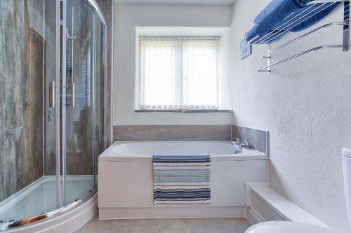 韦德布里奇Tregolls Farm Cottages的白色的浴室设有浴缸和淋浴。