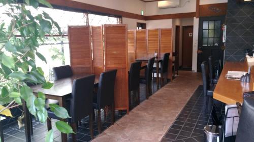 TochigiGuest House Kuranomachi ゲストハウス蔵の街的一间设有黑椅子和桌子的餐厅和一间房间