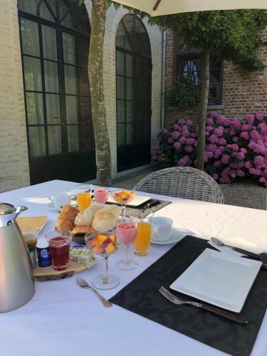 伊普尔Guesthouse Villa Vauban的餐桌,带食物和橙汁杯