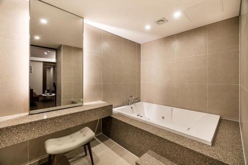 首尔WD酒店的带浴缸、水槽和凳子的浴室