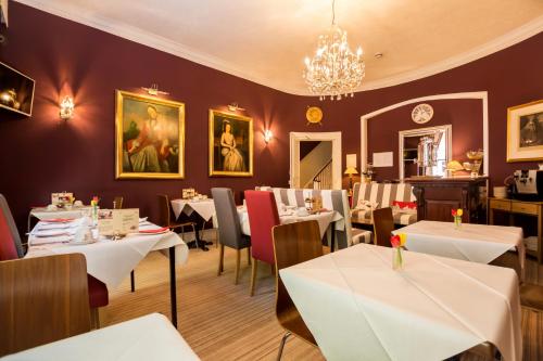 伦敦Arosfa Hotel London by Compass Hospitality的餐厅配有白色的桌椅和吊灯