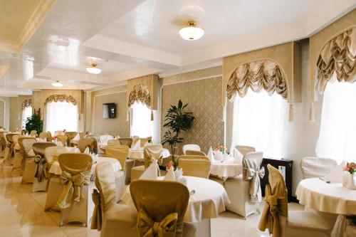 特鲁斯卡韦茨斯维迪亚兹度假酒店的餐厅设有白色的桌椅和窗户。