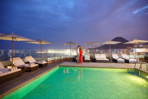 里约热内卢里约热内卢波尔图湾酒店的站在建筑物游泳池旁的女人