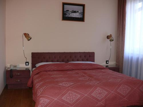 Balástya奥切德酒店的一间卧室配有一张带红色床罩和两盏灯的床。