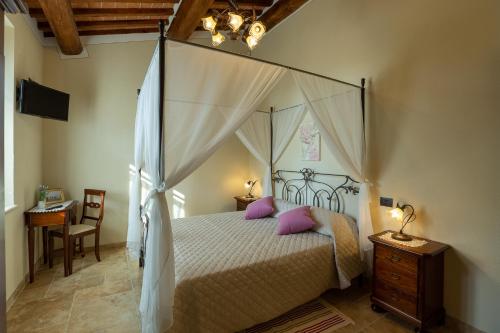 蒙特普齐亚诺Borgo Poggiardelli的卧室配有带粉红色枕头的天蓬床