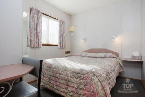 霍舍姆Horsham Holiday Park的一间卧室配有一张床、一张书桌和一个窗户。