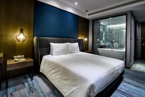 高雄钧怡大饭店的一间卧室设有一张大床和一个浴缸