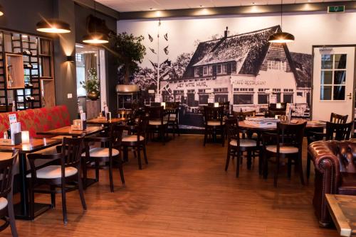 Olterterp赫特维特惠斯餐厅酒店 的一间设有桌椅的餐厅,墙上挂着壁画
