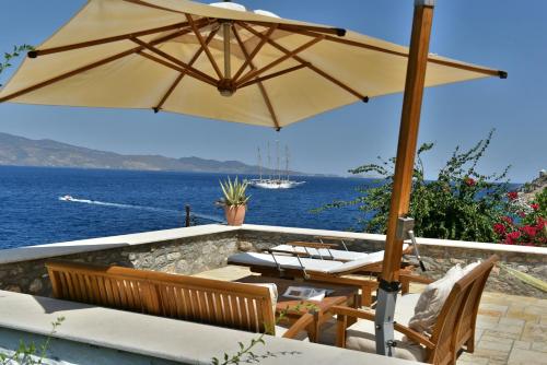 伊兹拉Hydra Kamini Beach Thea的一个带遮阳伞和椅子的庭院和大海