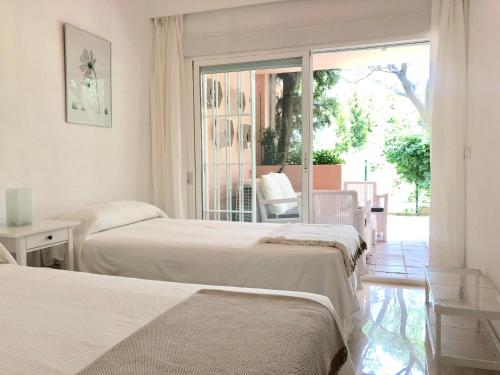 马贝拉Apartamento Guadalmina - Golf & Playa - Marbella的一间卧室设有两张床和一个带庭院的窗户。