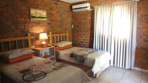 GrootfonteinPondoki Rest Camp的一间卧室设有两张床和砖墙