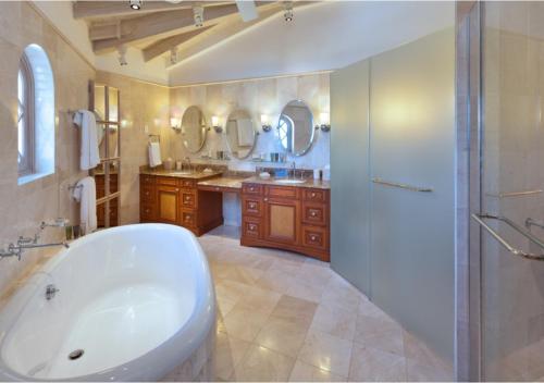 圣彼得教区圣彼得湾豪华度假公寓的带浴缸、两个盥洗盆和淋浴的浴室。