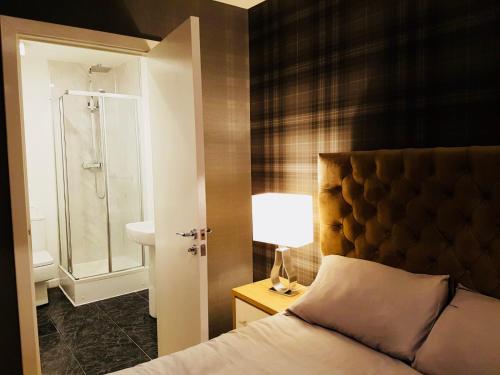 格拉斯哥Glasgow Central Station SKYLINE Apartment with Parking (2 bedrooms, 2 bathrooms, 1 living room-Kitchen)的一间卧室配有一张床,浴室设有淋浴。