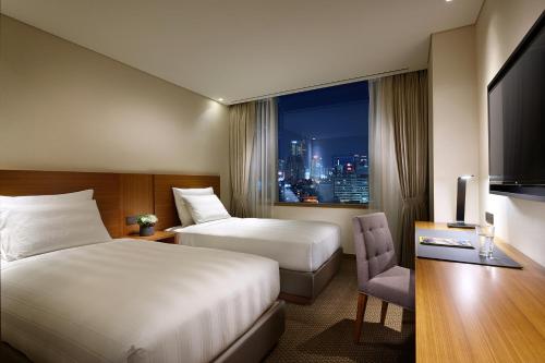 首尔LOTTE City Hotel Myeongdong的酒店客房设有两张床和窗户。