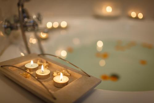 OʼOkiepOkiep Country Hotel的一组蜡烛放在木托盘上,放在浴缸前