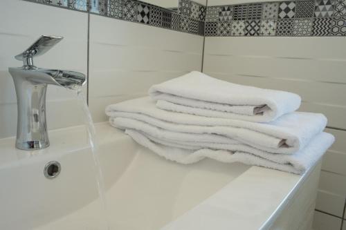 Le Bény-BocageAppart Hotel de la Souleuvre的浴室水槽上堆着的白色毛巾