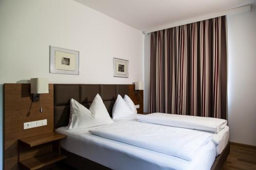 PetzenkirchenLandgasthof Barenwirt的一间卧室配有带白色床单和枕头的床。