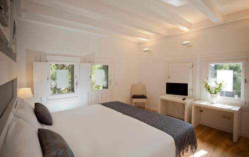 锡切斯锡切斯酒店的一间卧室配有一张床、一张书桌和一台电视