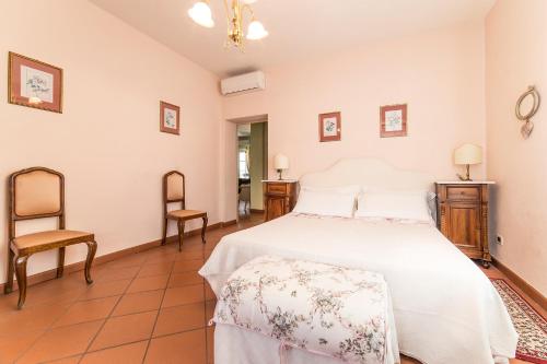 卢卡Appartamento La Terrazza的卧室配有白色的床和椅子