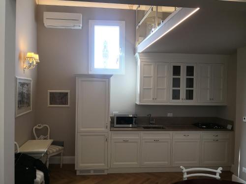 佛罗伦萨Santaelisabettafirenze1的厨房配有白色橱柜和窗户。