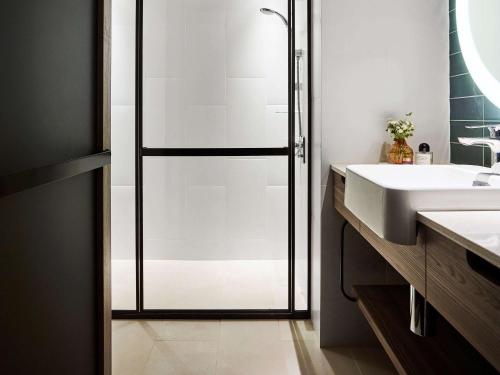悉尼诺富特悉尼达令广场酒店 的一间带玻璃淋浴和水槽的浴室