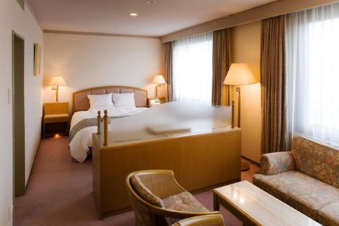 宇都宫东日本宇都宫酒店的酒店客房设有一张大床和一张沙发。